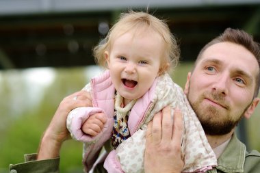 Küçük tatlı kız dışarıda oyun parkında eğleniyor. Genç baba küçük kızıyla oynuyor. Çocuklu aileler için bahar / yaz / sonbahar etkinliği. Mutlu ebeveynlik.