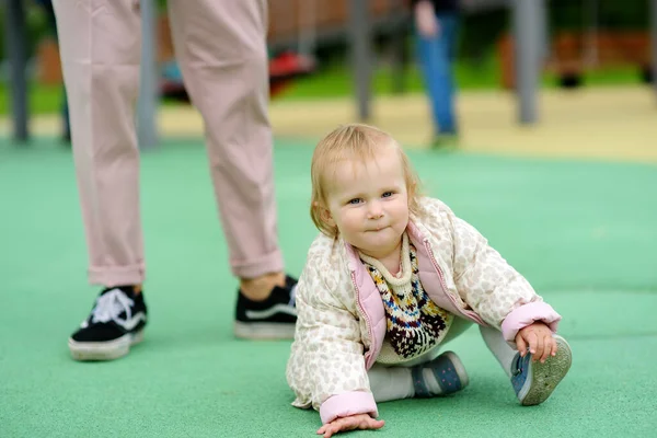 屋外の遊び場で楽しんでいるかわいい幼児の女の子 幼い父親は娘に歩くように教えている 赤ちゃんの第一歩 小さな子供を持つ家族のために歩く 幸せな親 — ストック写真