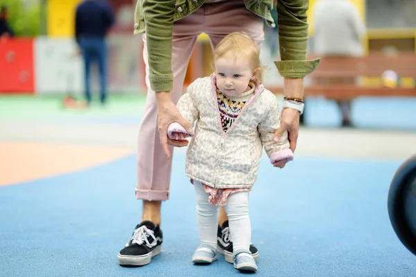 可爱的蹒跚学步的小女孩在户外操场上玩得很开心 年轻的父亲正在教他的小女儿走路 宝宝的第一步 为有小孩的家庭步行 快乐的父母 — 图库照片