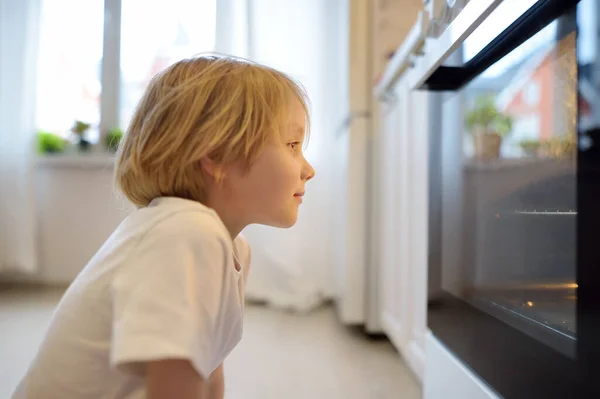 Hyvä Poika Istuu Lattialla Lähellä Keittiön Liesi Odottaa Piirakka Tai — kuvapankkivalokuva