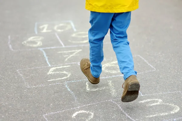 小男孩的腿和用沥青路面画的蹦床 春天的一天 孩子们在操场上玩跳房子游戏 儿童的户外活动 — 图库照片