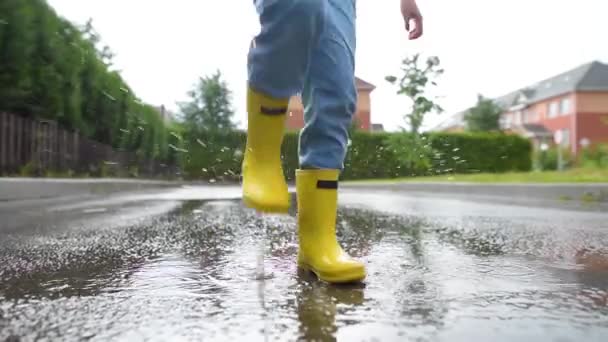 Kleine Jongen Met Gele Rubberen Laarzen Springend Een Plas Water — Stockvideo