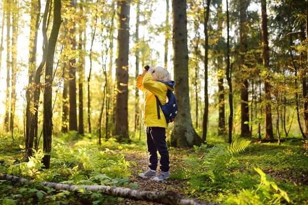 秋の森の中でハイキング中に双眼鏡を持つ小さな男の子のスカウト 子供は双眼鏡で見ている スカウト ハイキング観光 子供のための自然探索の概念 — ストック写真