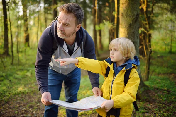 子供と彼の成熟した父親は一緒にハイキングし 自然を探索します 森の中でオリエンテーリング中に地図を見てお父さんと小さな男の子 子供のための冒険 スカウティング ハイキング観光 パパと息子 — ストック写真