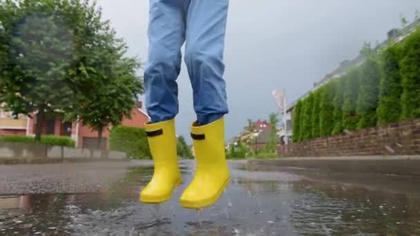 Chlapec Žlutých Gumových Botách Skákal Kaluži Vody Deštivého Letního Dne — Stock video