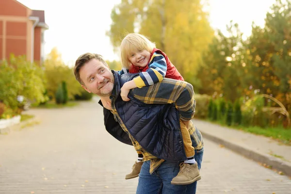 小さな男の子と彼の父親は 晴れた秋の日に散歩を楽しんでいます 父親は子供を一人で背負っている 新鮮な空気の中で質の高い家族の時間 子供たちと一緒にハイキング — ストック写真