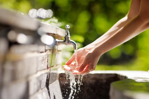 Woman washing hands in a city fountain — Stock Photo, Image