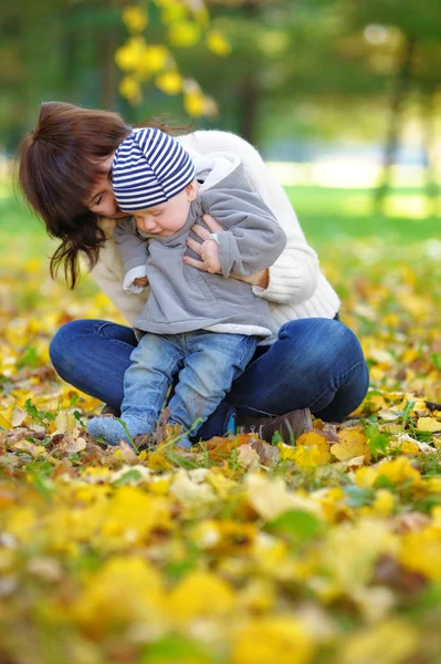 Lykkelig ung mor med sitt lille barn i høstparken – stockfoto