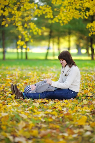 Joven madre con su bebé en el parque de otoño — Foto de Stock