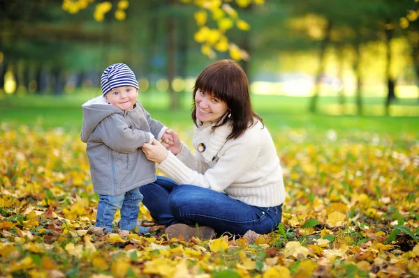 Jovem mãe com seu menino no parque de outono — Fotografia de Stock