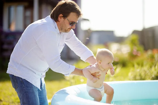 Middle age father and his baby son having fun by swimming pool