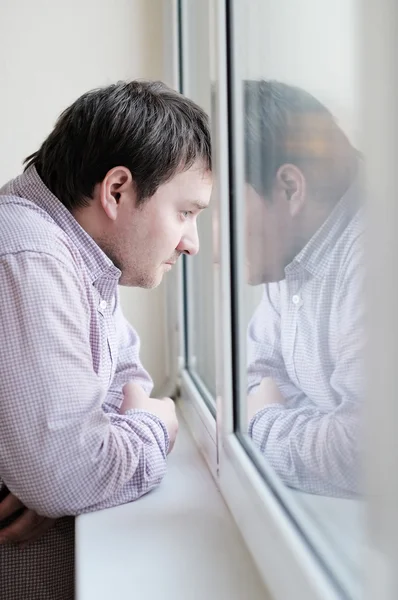 Мужчина средних лет смотрит в окно — стоковое фото