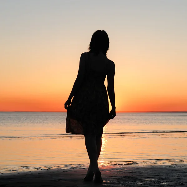 Vrouw als silhouet door de zee — Stockfoto