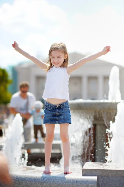 Préscolaire fille jouer avec une fontaine de la ville — Photo