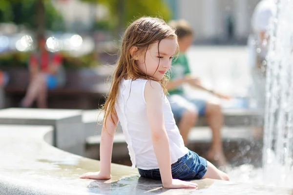 Petite fille préscolaire jouer avec une fontaine de la ville — Photo