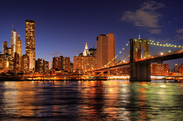 New York City Brooklyn Bridge with downtown skyline over East River at night