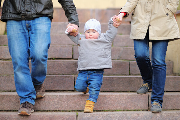 Toddler boy walking with his parents