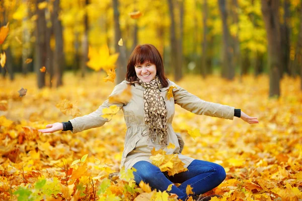 Jeune femme jouant avec les feuilles d'automne — Photo