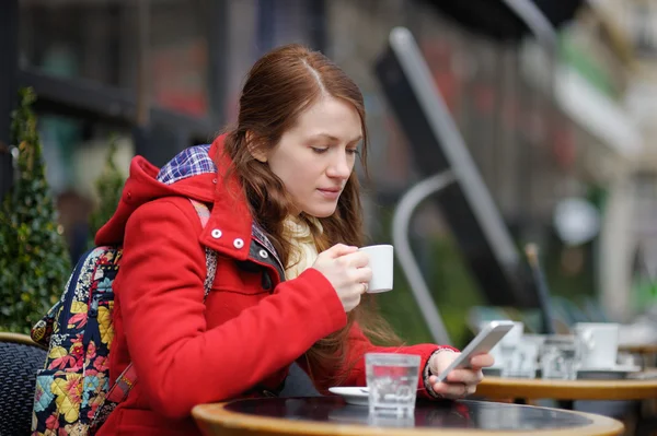 Jeune femme buvant du café et utilisant son téléphone intelligent — Photo