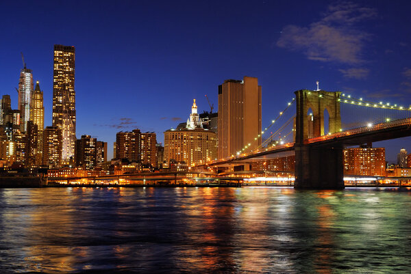 New York City Brooklyn Bridge with downtown skyline over East River at night