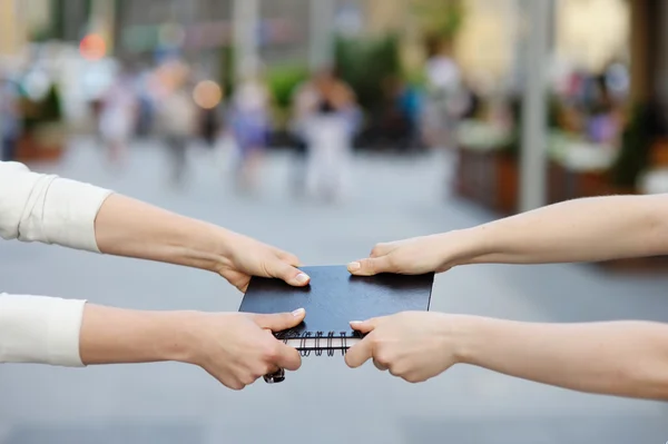 Two women pulls notebook towards each other — Stock Photo, Image