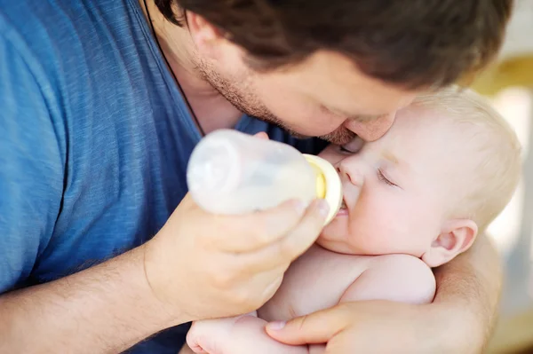 Baby drinking milk from bottle in father hands — Stock Photo, Image