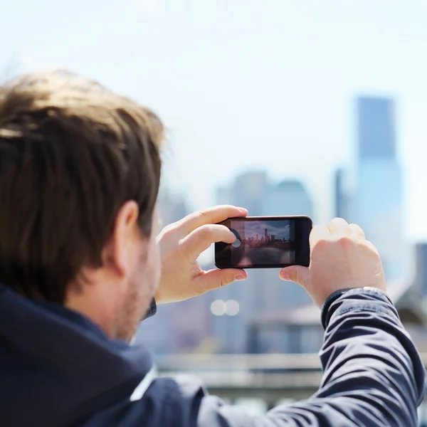 Турист фотографирует небоскребы на мобильный телефон — стоковое фото