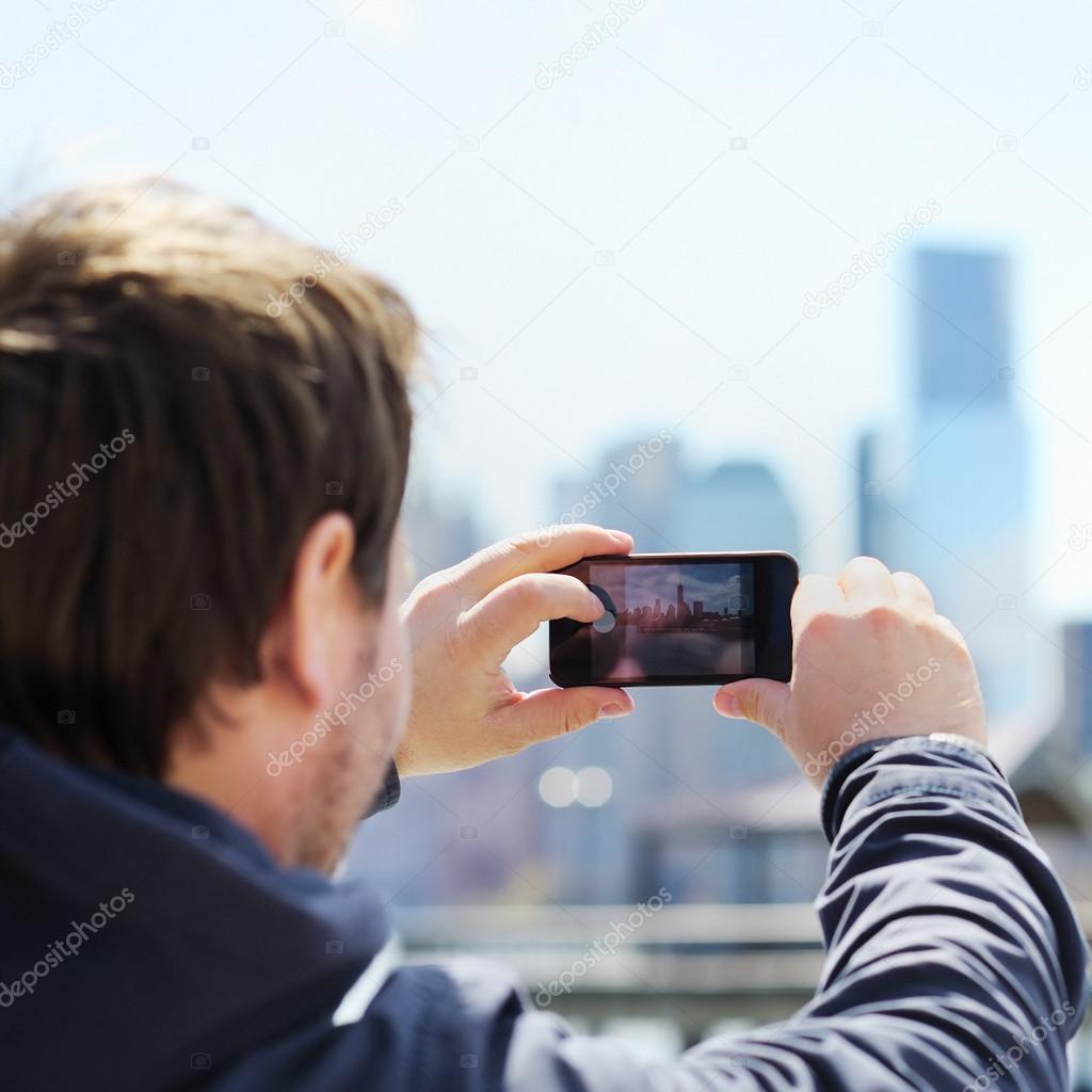 Tourist taking mobile photo of skyscrapers