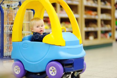 Alışveriş sepeti içinde oturan yürümeye başlayan çocuk