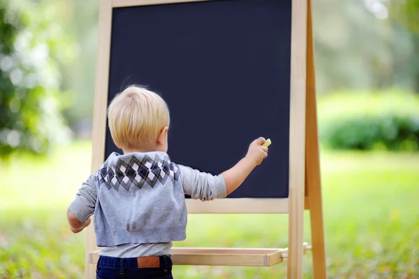 Criança desenho menino em pé por um quadro negro — Fotografia de Stock