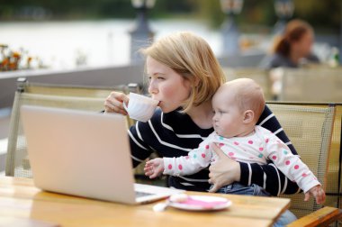 Genç anne ile bebeği çalışma veya onu laptop eğitim