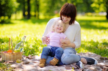 Young woman and her little son having a picnic clipart