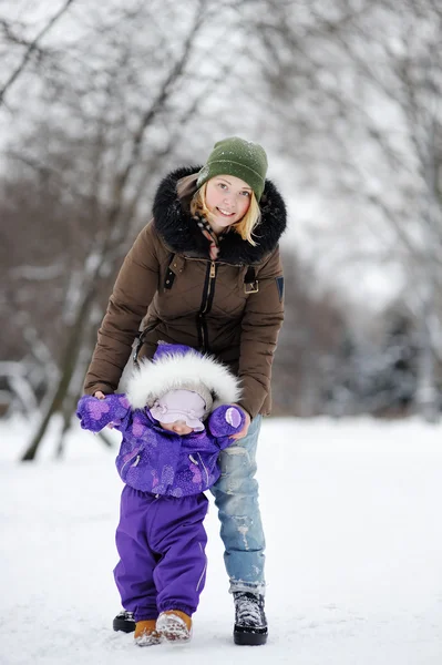 Jonge vrouw met haar peuter meisje in de winter park — Stockfoto