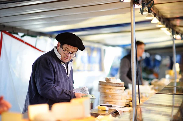 En leverantör som säljer ost på Paris farmer marknaden för jordbruksprodukter — Stockfoto