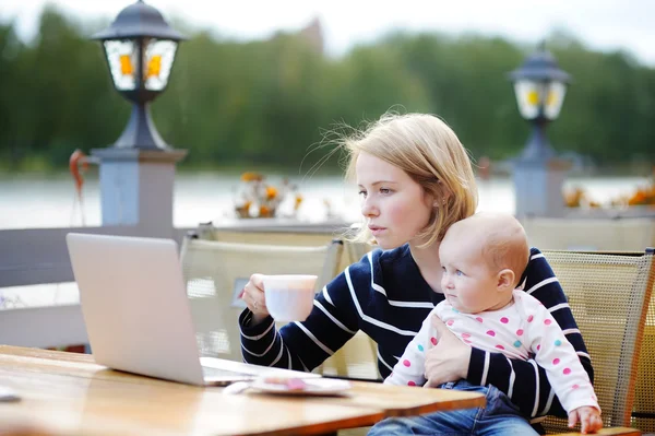 Молодая мать с ребенком работает или учится на ноутбуке — стоковое фото