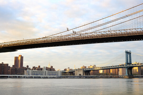 New York City Brooklyn Bridge with downtown skyline over East River at sunset