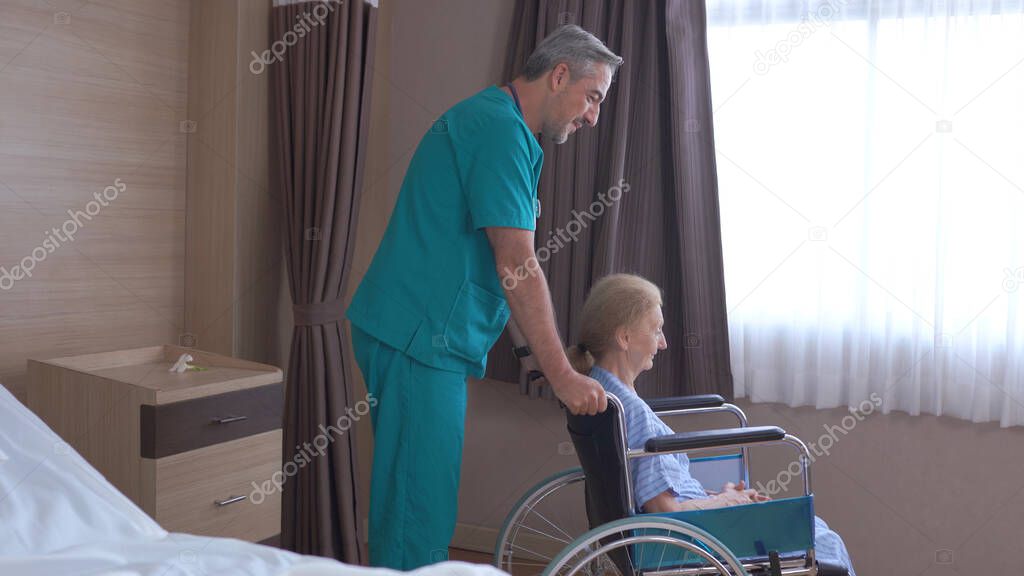 Doctor taking care of mature female patient sitting on wheelchair in hospital