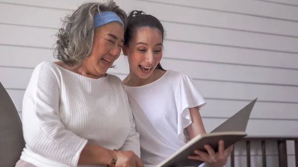 Ασιάτισσα Ηλικιωμένη Γυναίκα Και Κόρη Διαβάζουν Ένα Βιβλίο Στο Σπίτι — Φωτογραφία Αρχείου