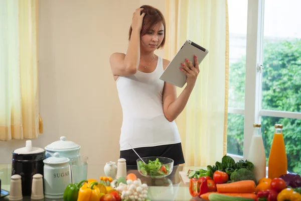 Mujer joven siguiendo la receta en la tableta digital —  Fotos de Stock