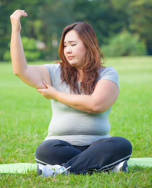 Ung kvinna kontrollera hennes arm fett — Stockfoto