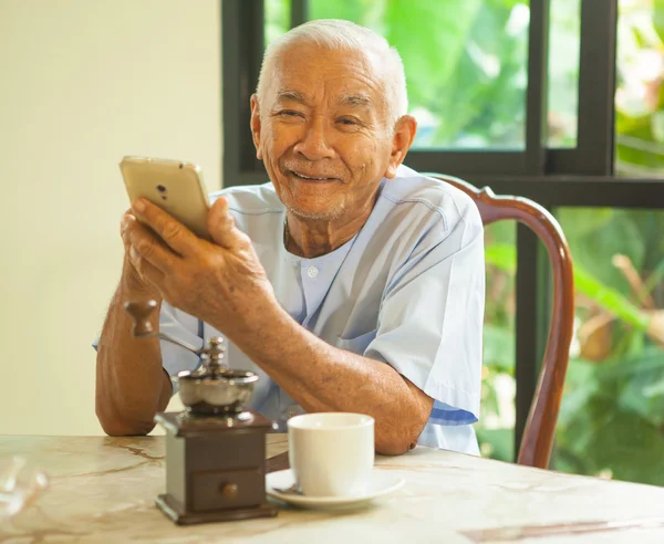 Feliz ásia sênior homem usando o celular em casa — Fotografia de Stock