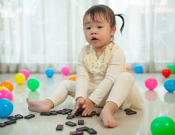 Malá dívka si hraje s černé domino — Stock fotografie