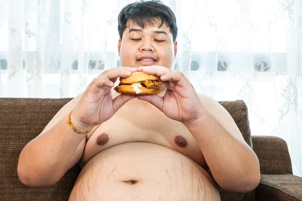 Gordo comendo hambúrguer sentado — Fotografia de Stock