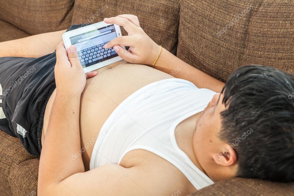Asian fat man Relaxing in the sofa with the tablet