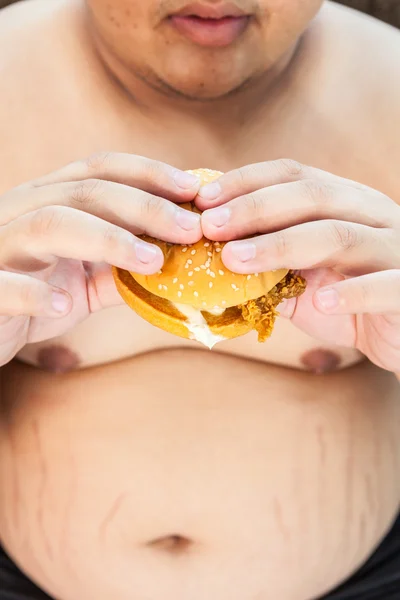 Grasso uomo mangiare hamburger seduto — Foto Stock