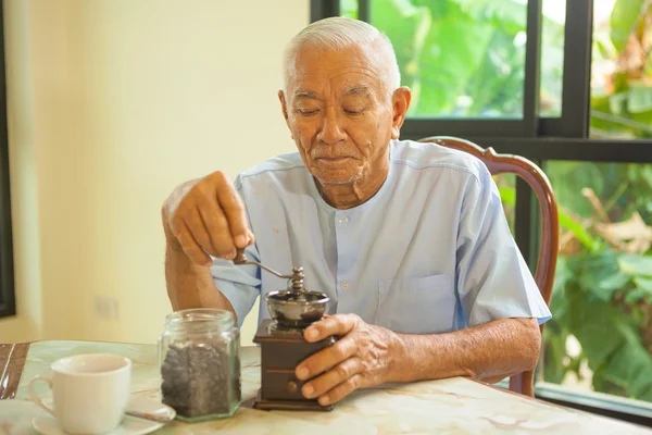 亚洲老人与老式的咖啡研磨机 — 图库照片