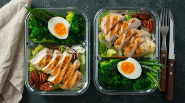 Taze fasulye, tavuk göğsü ve brokoli ile sağlıklı yemek hazırlama kapları. Koyu beton arka planda, beslenme çantasında Keto diyeti için bir set yiyecek. Üst görünüm