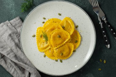 Koyu beton arka planda tereyağlı ev yapımı Balkabağı Ravioli. Üst görünüm.