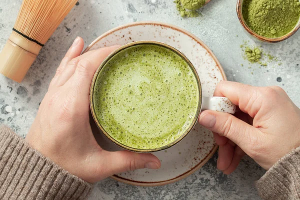 Cup of Matcha Green Tea in woman hands. Top view. flat lay.