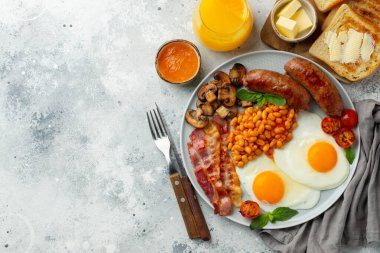 Yağda yumurta, sosis, pastırma, fasulye, kızarmış ekmek ve hafif taşlı fonda kahve ile tam İngiliz kahvaltısı. Kopyalama alanı olan. Üst görünüm